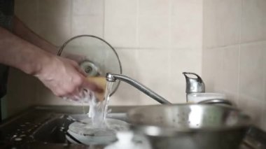 Erkek elleri mutfakta bulaşık yıkıyor.