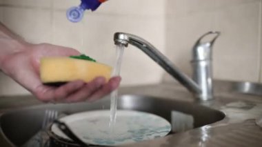 Mutfak lavabosunda bulaşık yıkayan insanlar.