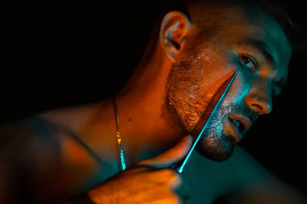 Male shaving with a large kitchen knife.