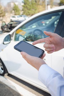 akıllı telefon caddede erkeklerin elinde, arabanın arka planında.