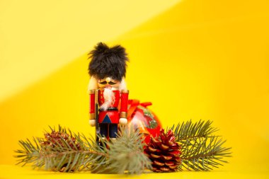 Noel oyuncağı fındıkkıran. Sarı arka planda şenlik süsleri var..
