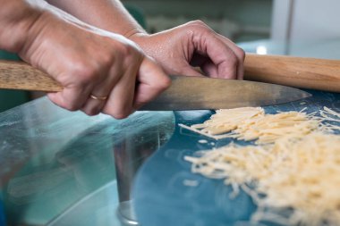 Tanınmayan bir kadın erişte keser. Kadınların elleri yakın plan..