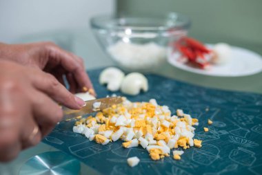 Bir kadın masada haşlanmış yumurta dilimliyor..