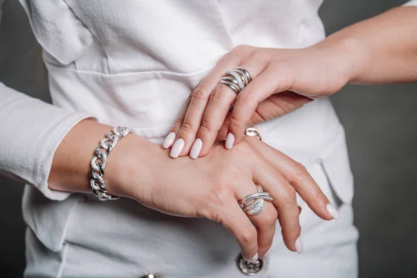Beautiful jewelry, rings and a bracelet on womens hands in a white jacket — Stock Photo, Image