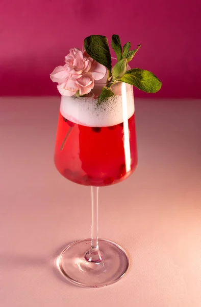 Coquetel festivo vermelho com uma flor em um fundo rosa — Fotografia de Stock