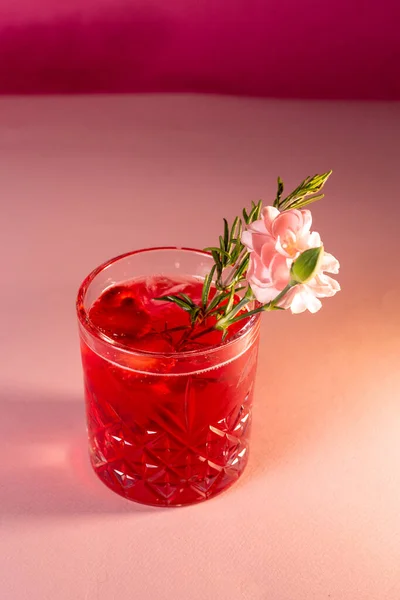 Coquetel festivo vermelho com uma flor em um fundo rosa — Fotografia de Stock