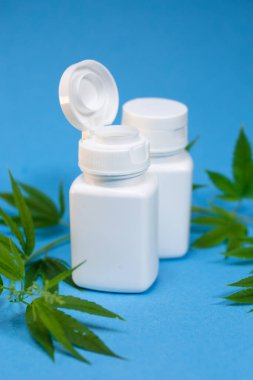 Mavi arka planda beyaz kavanoz ve esrar.