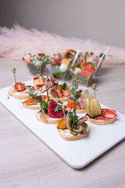 Beyaz tabakta çeşitli bruschetta ve sandviçler..