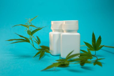 Mavi arka planda beyaz kavanoz ve esrar.