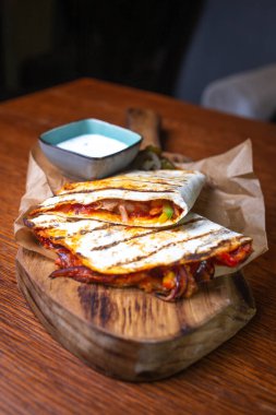 Tahta tepside doldurulmuş ve soslu tortilla..