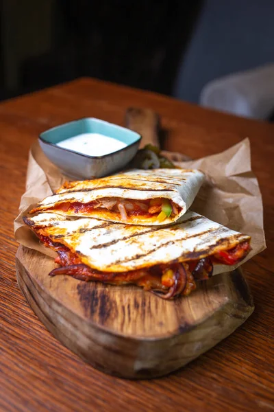 Tahta tepside doldurulmuş ve soslu tortilla..