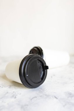 Arka planda beyaz karton kahve fincanları var. Tek kullanımlık tablo takımı