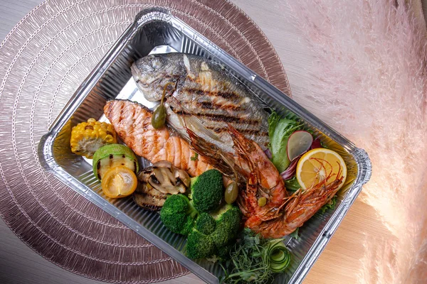 foil packaging of seafood delivery with vegetables top view.