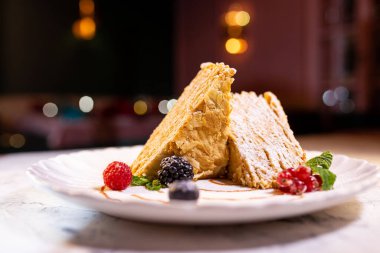 Beyaz tabakta böğürtlenli Napolyon tatlısı..