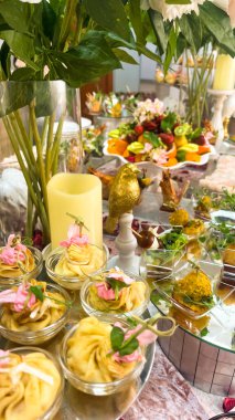 Şenlik masasının dekorasyonu. Çiçeklerle süslenmiş çeşitli yemekler ve atıştırmalıklar.