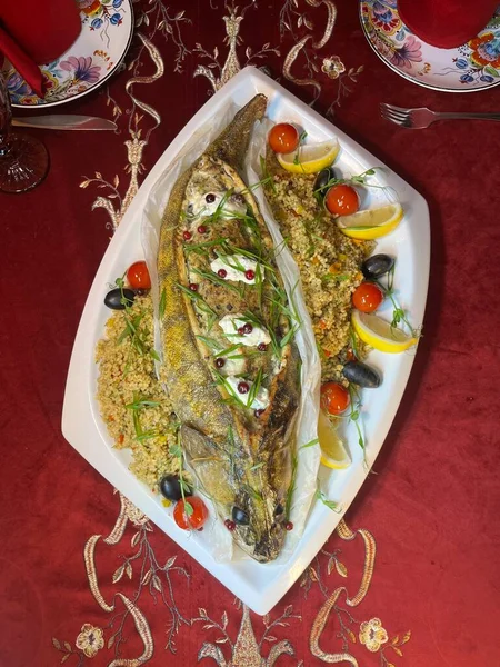 Dishes of baked fish with a side dish on a white plate top view.