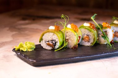 Japon yemeği, siyah tabakta peynirli pirinç rulosu..