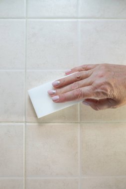 Beyaz bir melamin süngerle el fayansları yıkar..