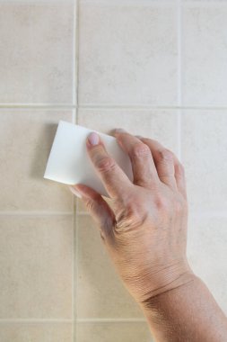 Beyaz bir melamin süngerle el fayansları yıkar..