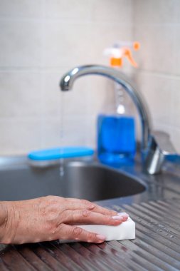 Mutfak temizliği. Bir kadın lavaboyu beyaz bir süngerle yıkıyor..