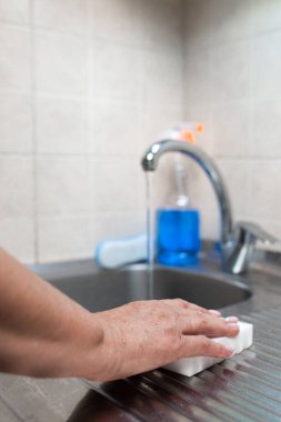 Mutfağı süngerle temizleyen bir kadının eli..