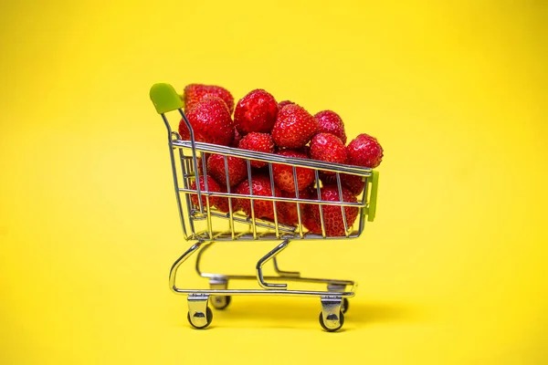 Een Supermarktkar Vol Rode Aardbeien Een Gele Achtergrond — Stockfoto