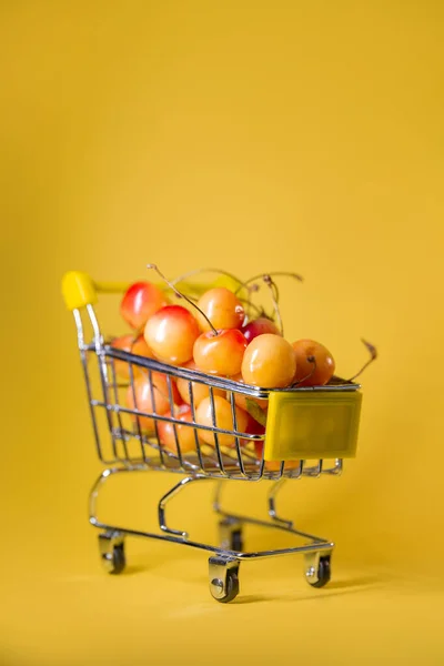 Тележка Супермаркета Желтыми Вишнями Желтом Фоне — стоковое фото