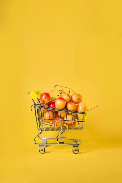 Тележка Супермаркета Желтыми Вишнями Желтом Фоне — стоковое фото