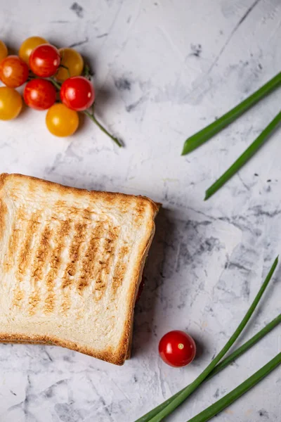 sandwich with chicken in plastic packaging and fresh vegetables on a light background.