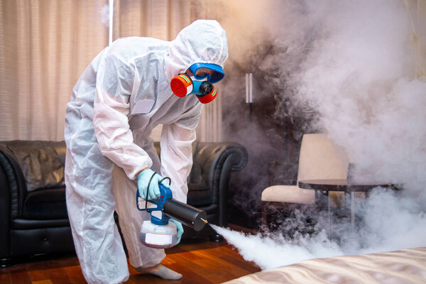 disinfection of the room against viruses. Man in quarantine clothes disinfecting room.