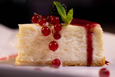 Böğürtlenli beyaz tabakta taze New York peynirli keki. Bir yemek restoranında tatlı servisi..