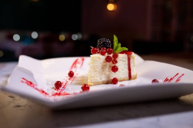 Böğürtlenli beyaz tabakta taze New York peynirli keki. Bir yemek restoranında tatlı servisi..