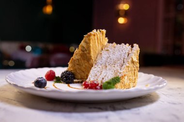 Beyaz tabakta böğürtlenli Napolyon keki. Lokantada tatlı servisi..