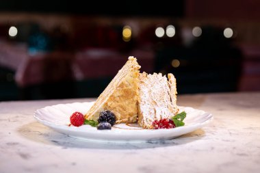 Beyaz tabakta böğürtlenli Napolyon keki. Lokantada tatlı servisi..