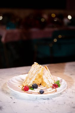 Beyaz tabakta böğürtlenli Napolyon keki. Lokantada tatlı servisi..