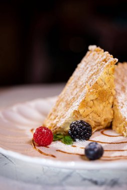 Beyaz tabakta böğürtlenli Napolyon keki. Lokantada tatlı servisi..