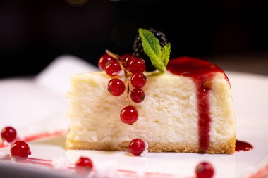 Böğürtlenli beyaz tabakta taze New York peynirli keki. Bir yemek restoranında tatlı servisi..