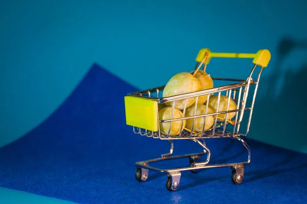 Pruimen Een Kleine Supermarkt Kar Een Blauwe Achtergrond — Stockfoto