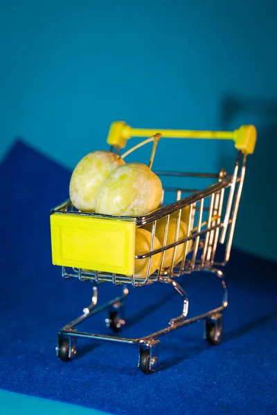 Pruimen Een Kleine Supermarkt Kar Een Blauwe Achtergrond — Stockfoto