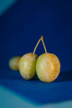 plums with foliage on a blue background.
