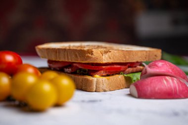sandwich of bread toasts and vegetables on a wooden board.