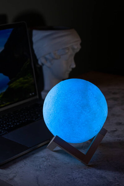 Light the lamp on the desktop. A modern table lamp illuminates the background of the wall