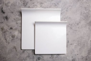 white ceramic square plates on a concrete background.