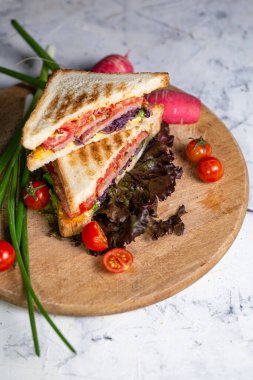 juicy crispy sandwich with ham and vegetables close-up on the board.