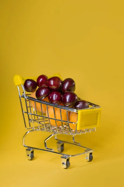 Supermarkt Kar Gevuld Met Abrikozen Kersen Een Gele Achtergrond — Stockfoto