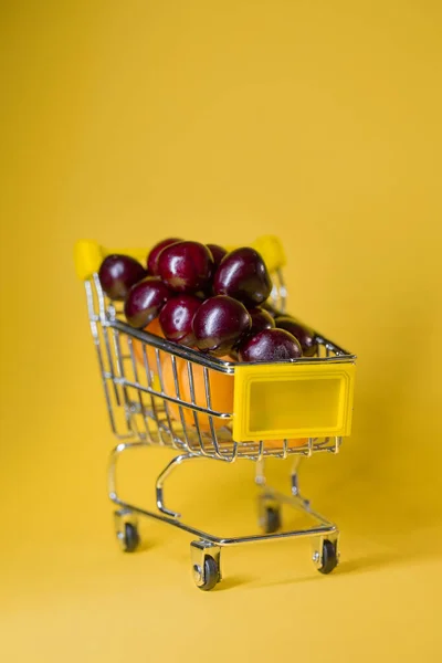 Mataffären Vagnen Fylld Med Aprikoser Och Körsbär Gul Bakgrund — Stockfoto