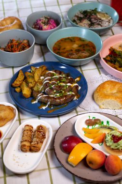 Yemek masasında patates ve farklı tabaklar bulunan ev yapımı sosisler.