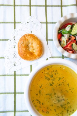 chicken soup with salad and bread on a bell tablecloth.