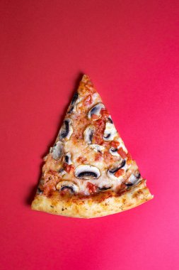 Kırmızı arka planda mantarlı bir dilim pizza..