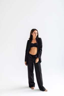 Beyaz arka planda poz veren gülümseyen çekici iş kadınının tam boy portresi.